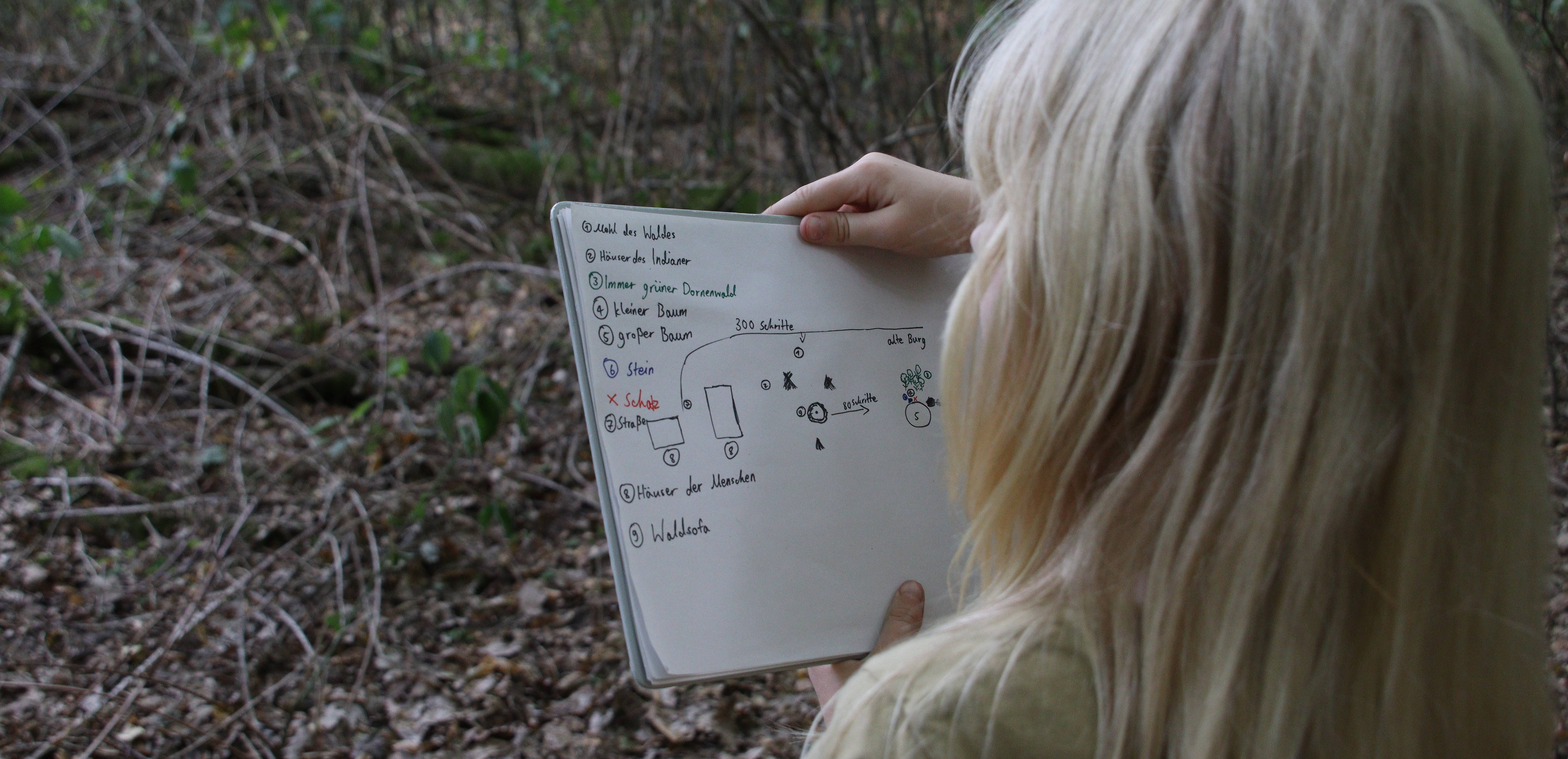 Impressionen FUNKT 2022: blondes Kind liest im Wald einen Plan