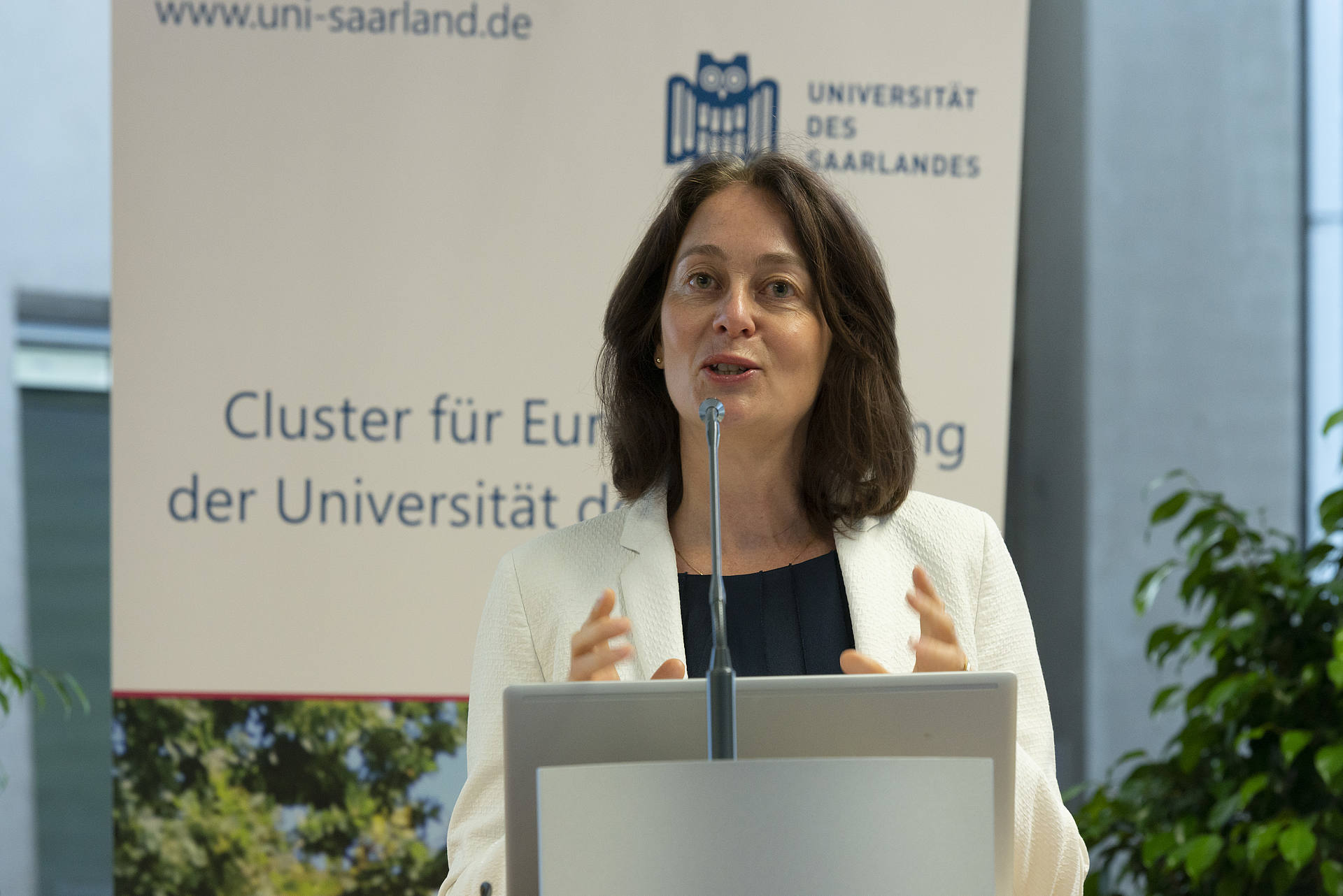 Katarina Barley, Mitglied und Vizepräsidentin des Europäischen Parlaments, hält die Keynote der 3. Saarbrücker Europa-Konferenz. Sie steht am Rednerinnenpult vor dem Roll-up des Clusters für Europaforschung der Universität des Saarlandes.