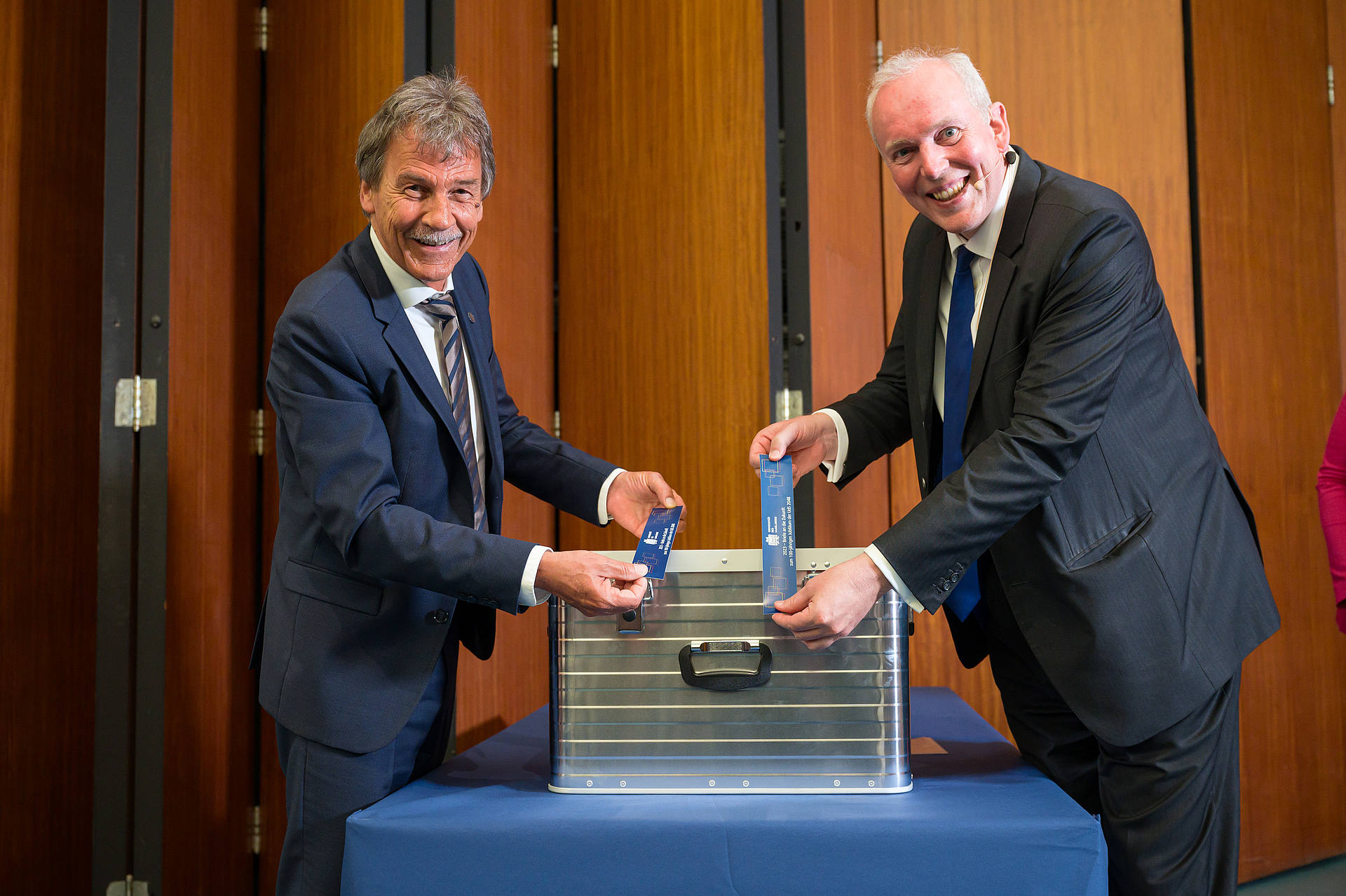 Universitätspräsident Prof. Dr. Manfred Schmitt und Finanzminister Jakob von Weizsäcker versiegeln mit Aufklebern die Zeitkapsel (ein Aluminium-Koffer)