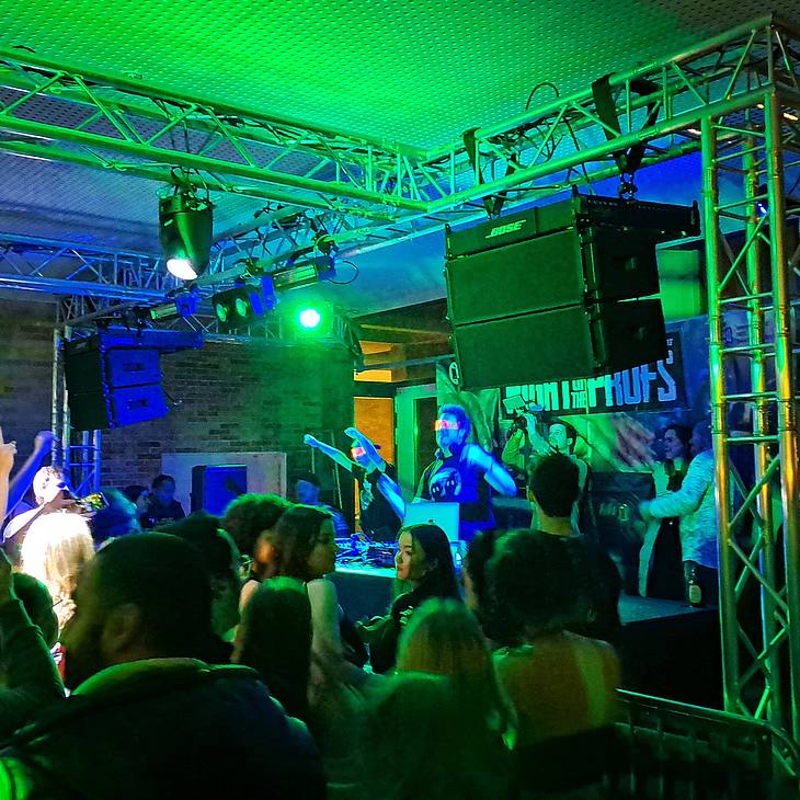 in grünem Licht tanzende Menschen vor der Bühne mit zwei DJs