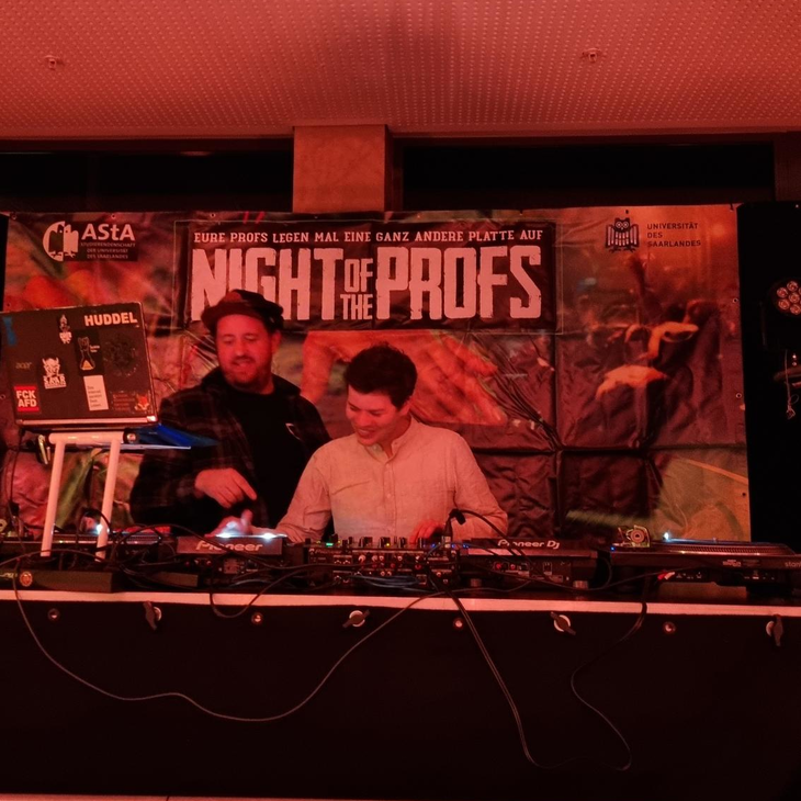 zwei DJs am Mischpult in rotem Licht