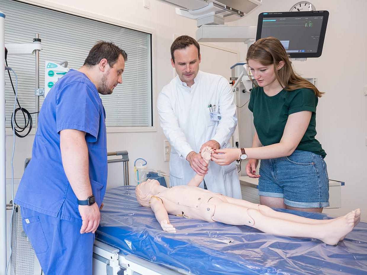 Zwei Ärzte und eine Studentin untersuchen eine Dummy-Puppe