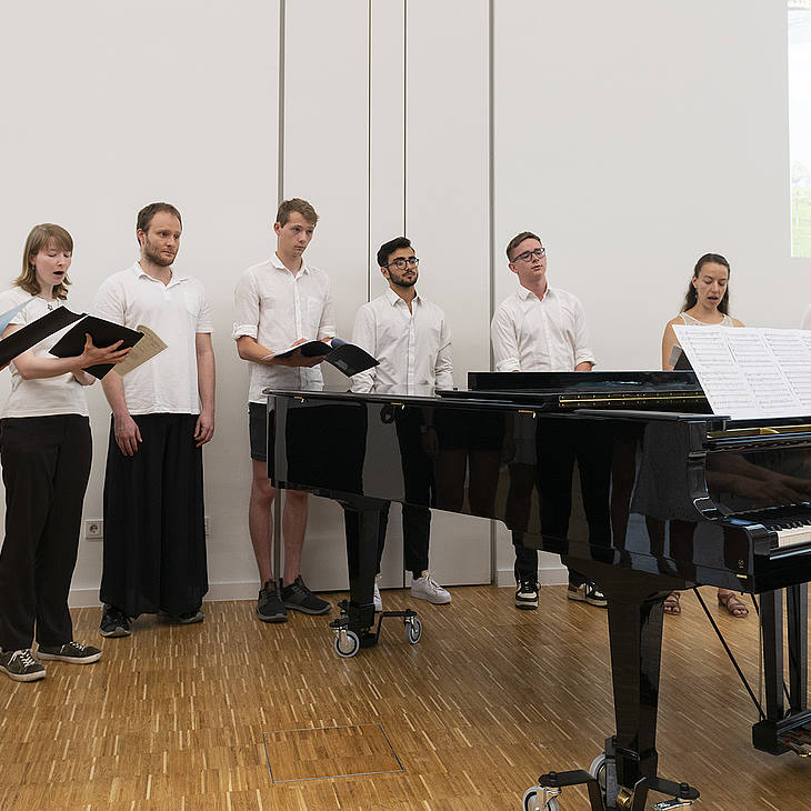 Der Universitätschor Homburg singt, der Chorleiter Sebastian Brand spielt am Klavierflügel