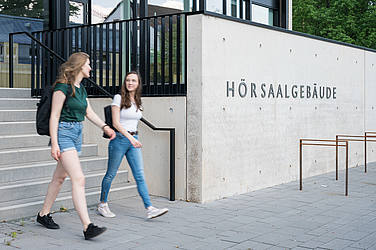 Zwei Studentinnen kommen aus dem Hörsaalgebäude der Medizin auf dem Campus Homburg.