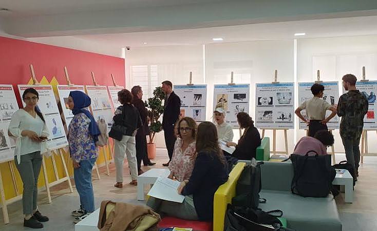 Menschen im Austausch rund um Aufstelltafeln mit Informationen im Rahmen der ersten Konferenz im April 2023 in Tunis