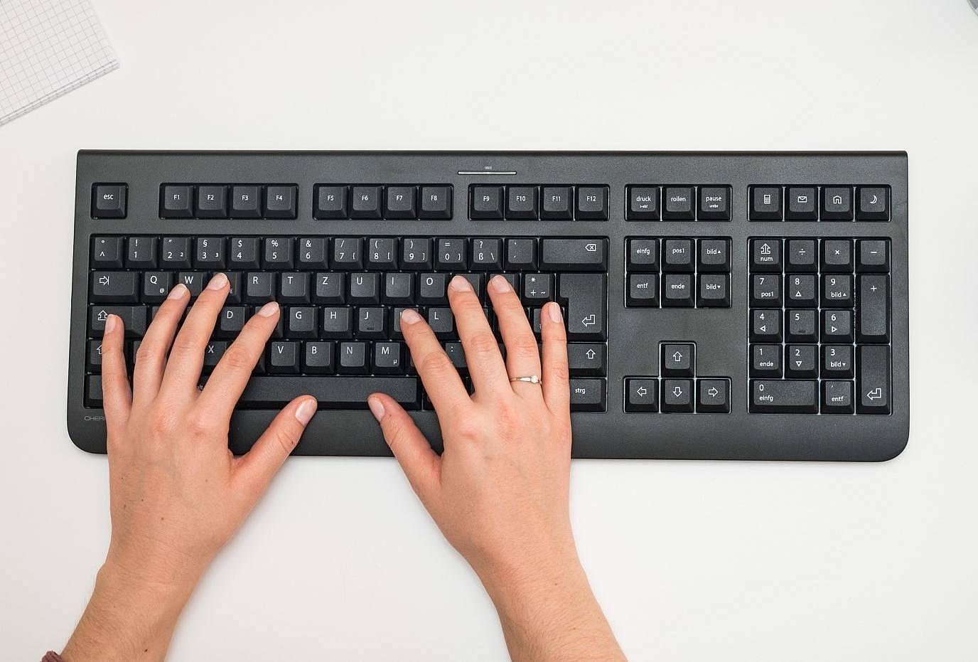Draufsicht auf eine Tastatur mit zwei Händen und eine Maus