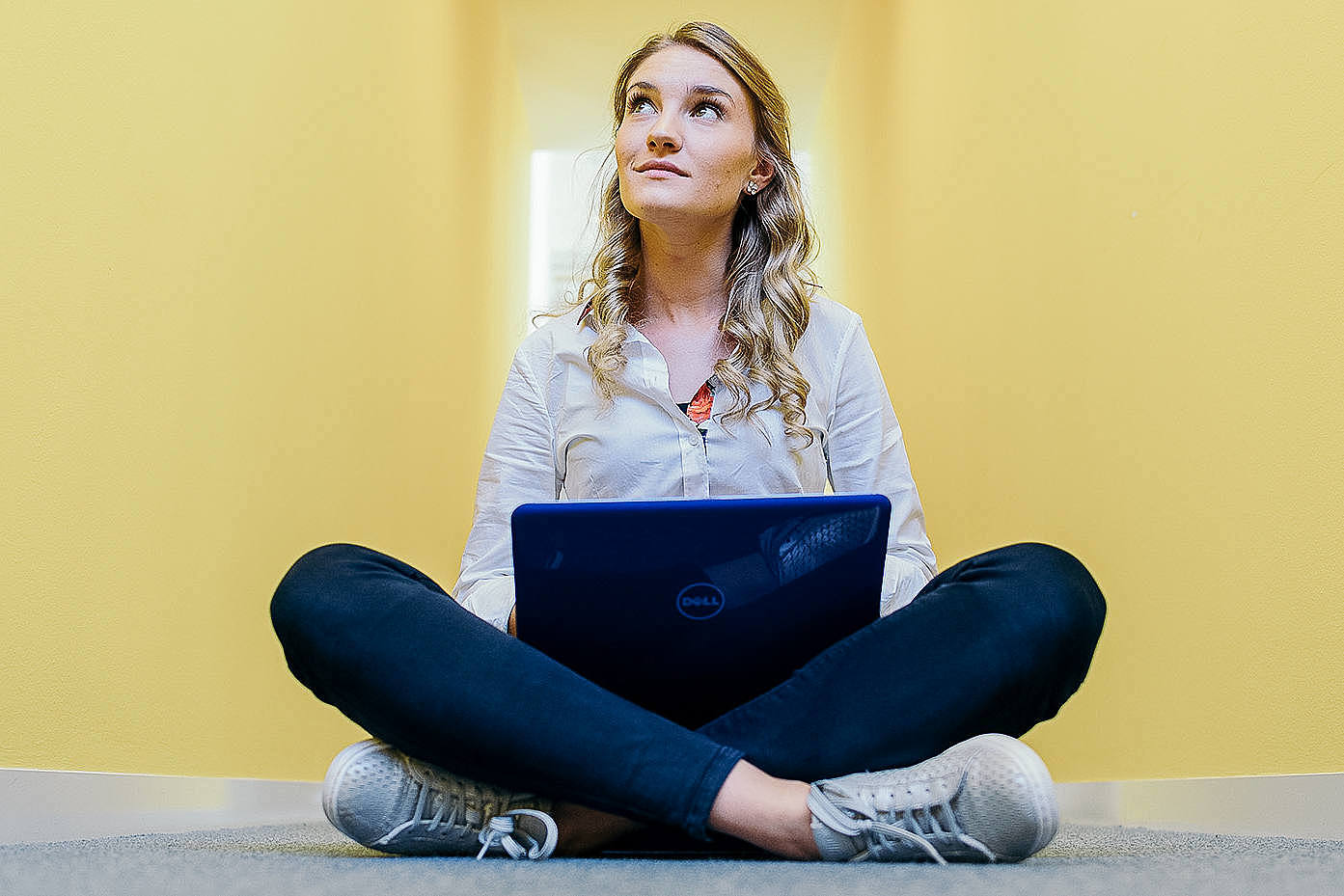 Studentin im Schneidersitz mit einem Laptop
