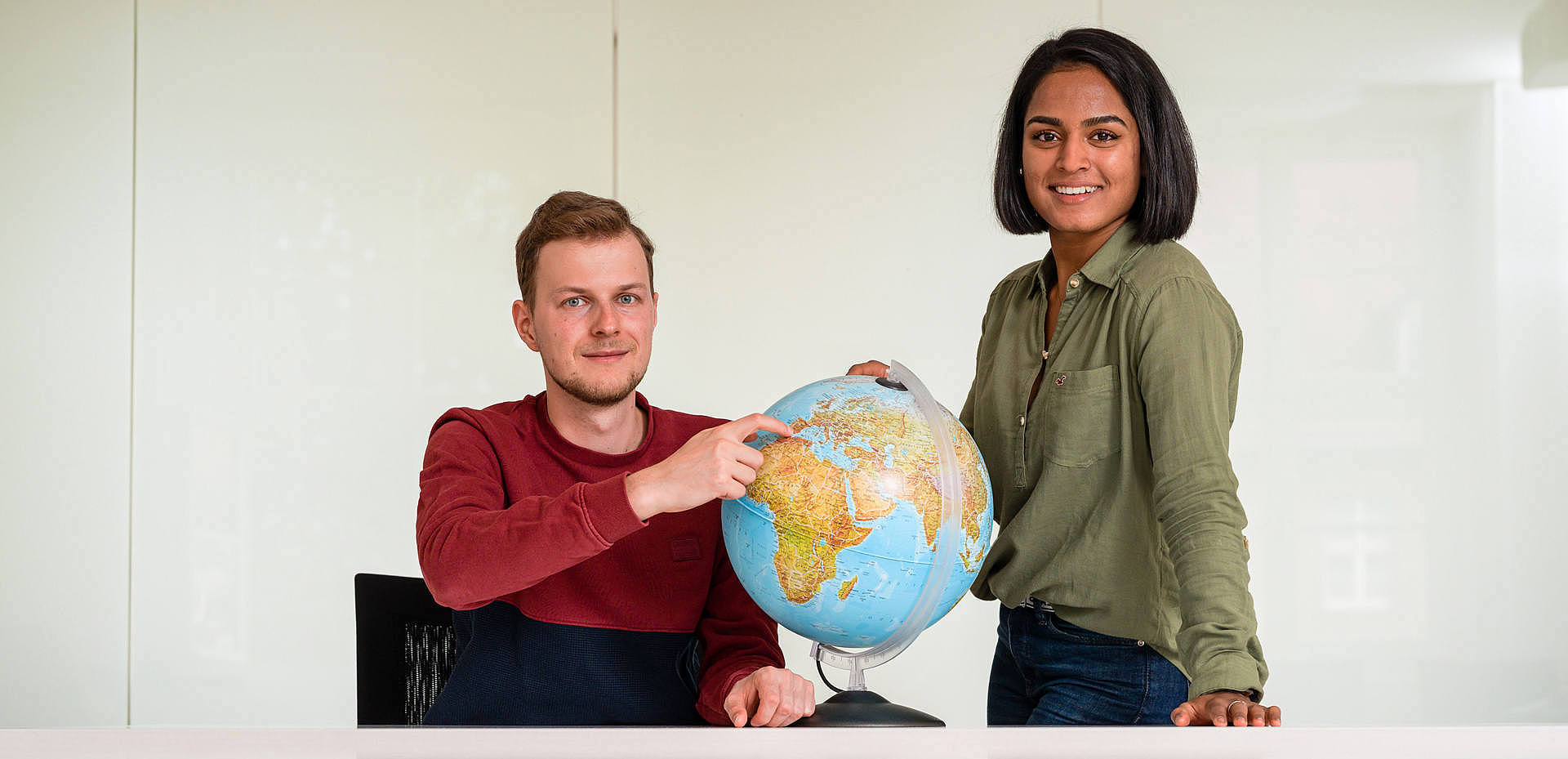 Ein junger Mann und eine junge Frau mit einem Globus