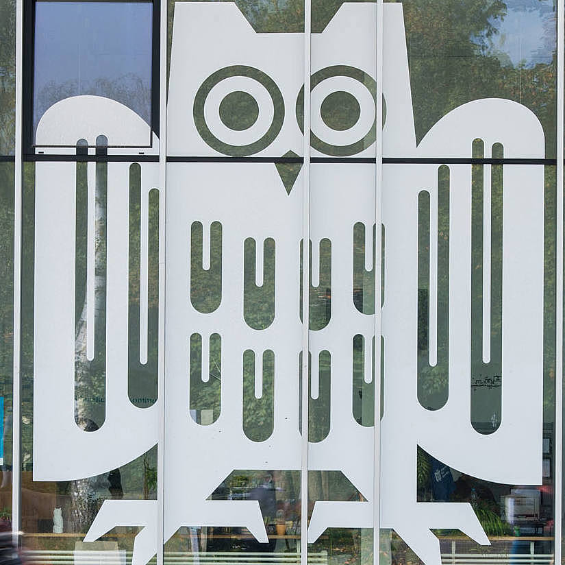 Ausschnitt eines Glasbaus mit großem weißen Logo der Universität des Saarlandes auf den Fenstern