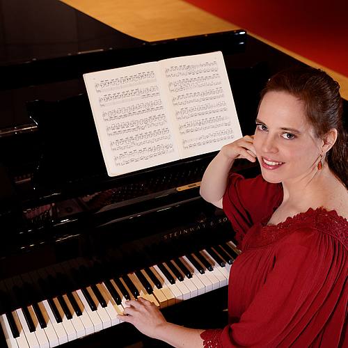 Frau im roten Kleid am Klavier