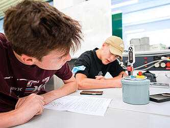 Zwei Schüler schauen im Labor auf ein Messgerät.