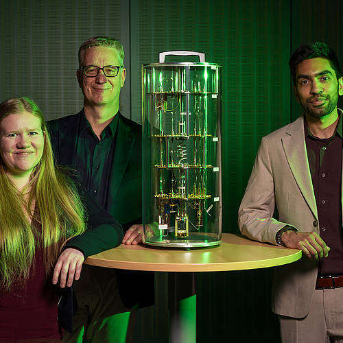 Die drei Wissenschaftler stehen um ein Modell eines Quantencomputers.