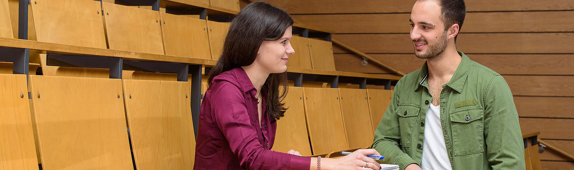 Zwei Studierende unterhalten sich in einem Hörsaal der Universität des Saarlandes