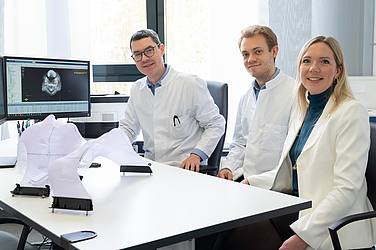 Drei Ärzte an einem Schreibtisch vor einem Monitor