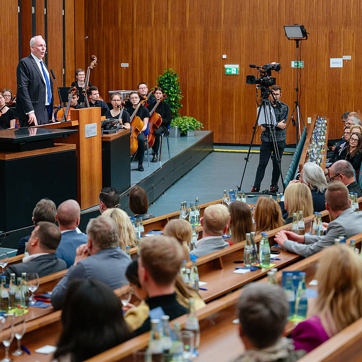 Jakob von Weizsäcker, Minister der Finanzen und für Wissenschaft des Saarlandes, hält ein Grußwort, die Kamera filmt ihn dabei, um das Ereignis zeitgleich streamen zu können