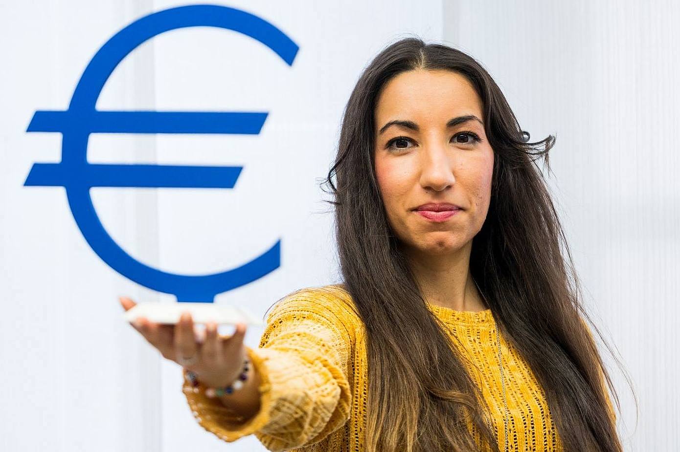 Studentin hält ein großes Euro-Symbol vor sich hoch