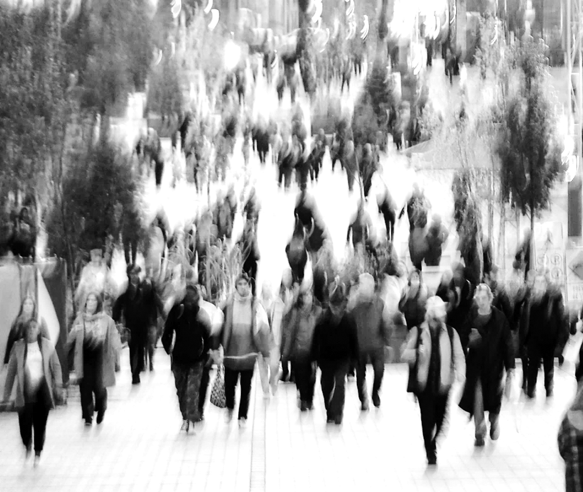 Verschwommene schwarz-weiß Darstellung von Menschen in einer Fußgängerzone 