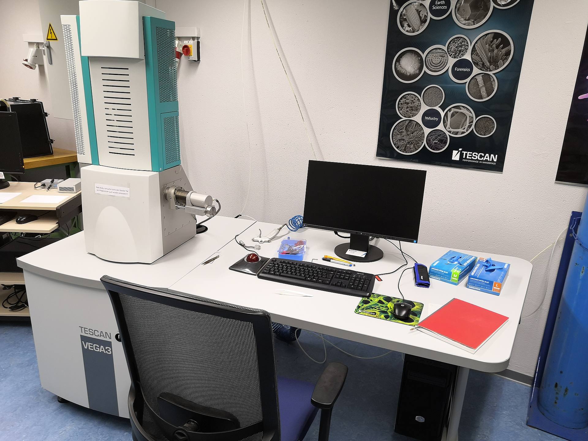 Rasterelektronenmikroskop und Schreibtisch in einem Labor.