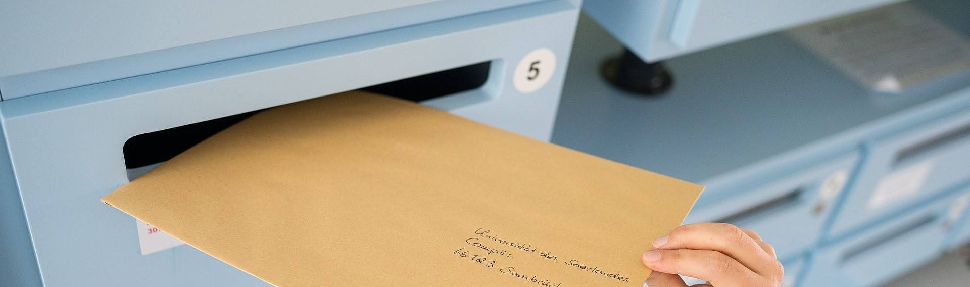 Ein an die Universität des Saarlandes adressierter Brief wird in einen Briefkasten geworfen