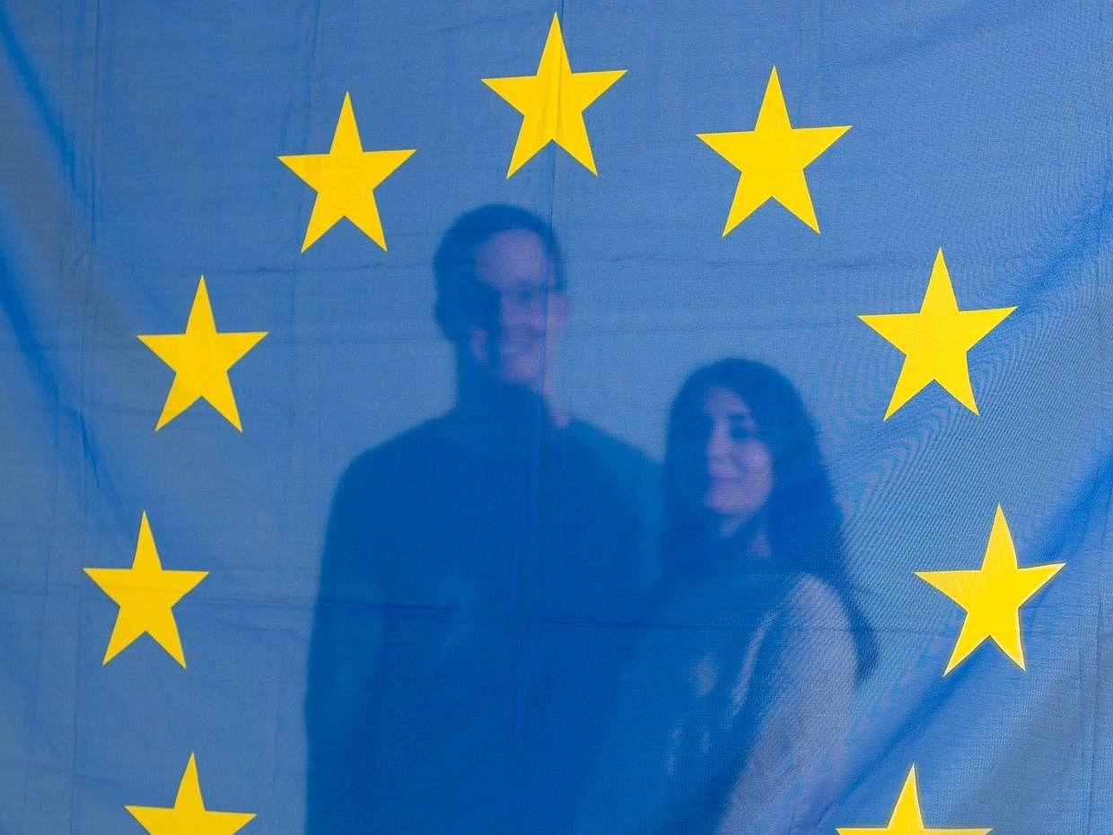 Zwei Studierende stehen hinter einer Europaflagge