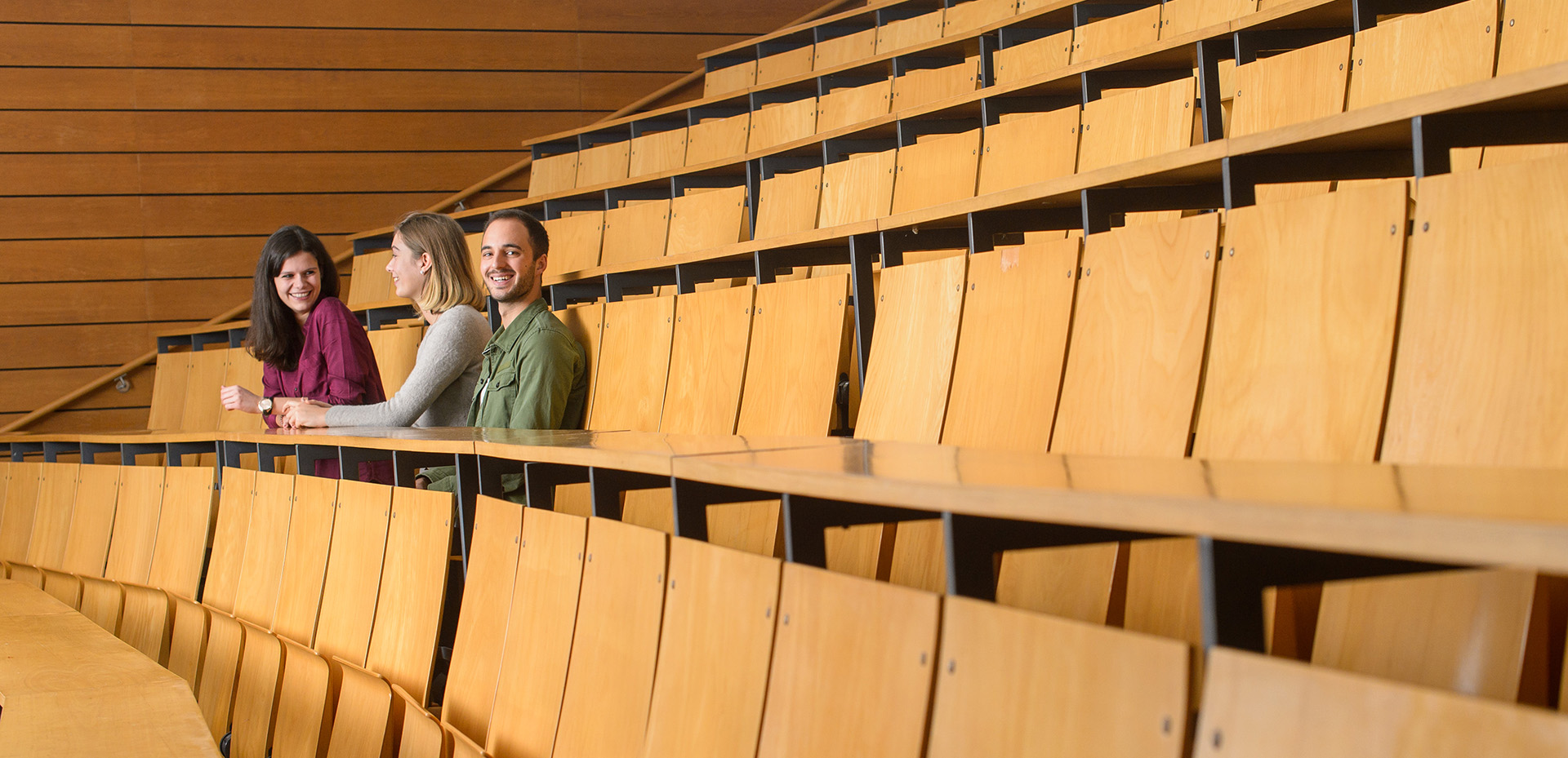 Drei Studierende sitzen am Rand eines Hörsaals der Universität des Saarlandes