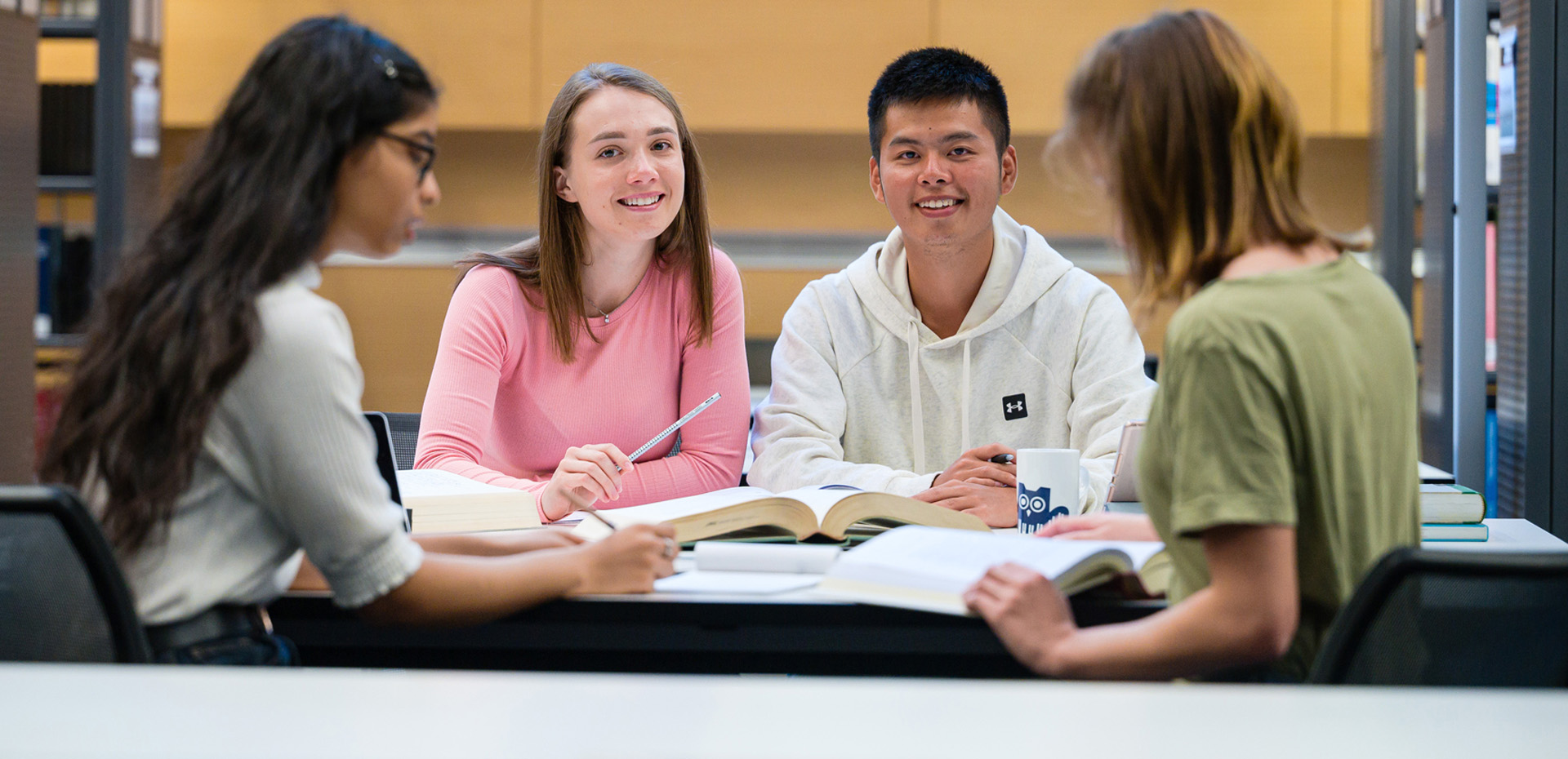 Vier Studierende lernen gemeinsam an einem Tisch in der Bibliothek.