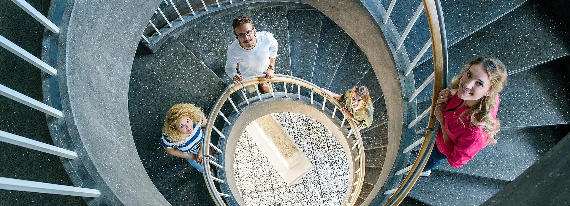 Aufsicht auf eine Wandeltreppe, in der vier Studierende stehen