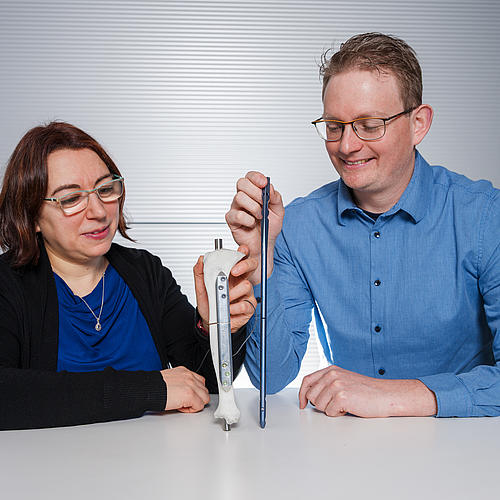 Die beiden Wissenschaftler halten den Prototyp einer smarten Implantatplatte und einen Marknagel in die Kamera