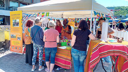 Bunter Stand mit People of Colour und interessierten Besuchern davor.