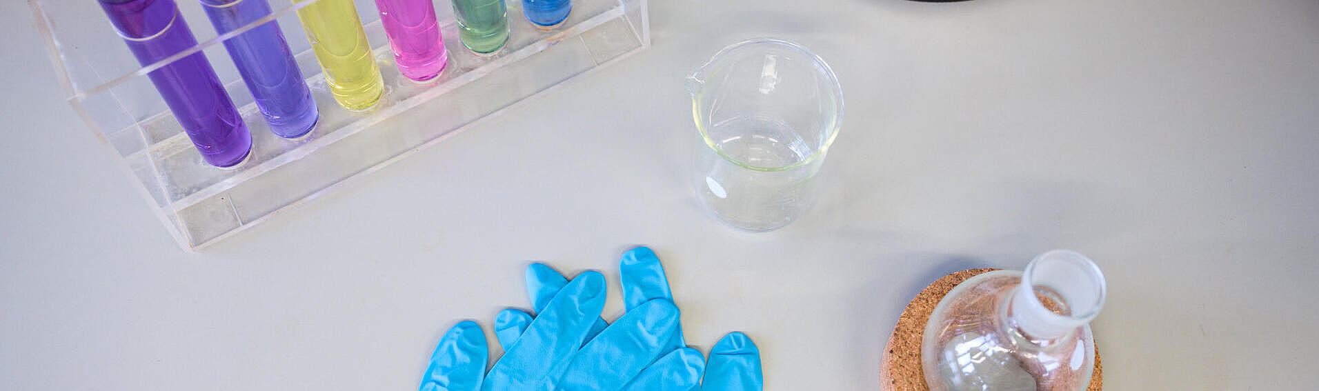 Zwei blaue Plastikhandschuhe liegen auf einem Labortisch.