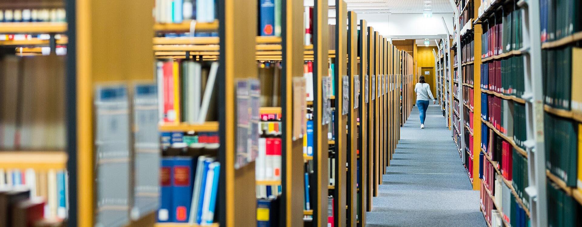 Bücherregale in einer Bibliothek mit einer Studentin im Gang