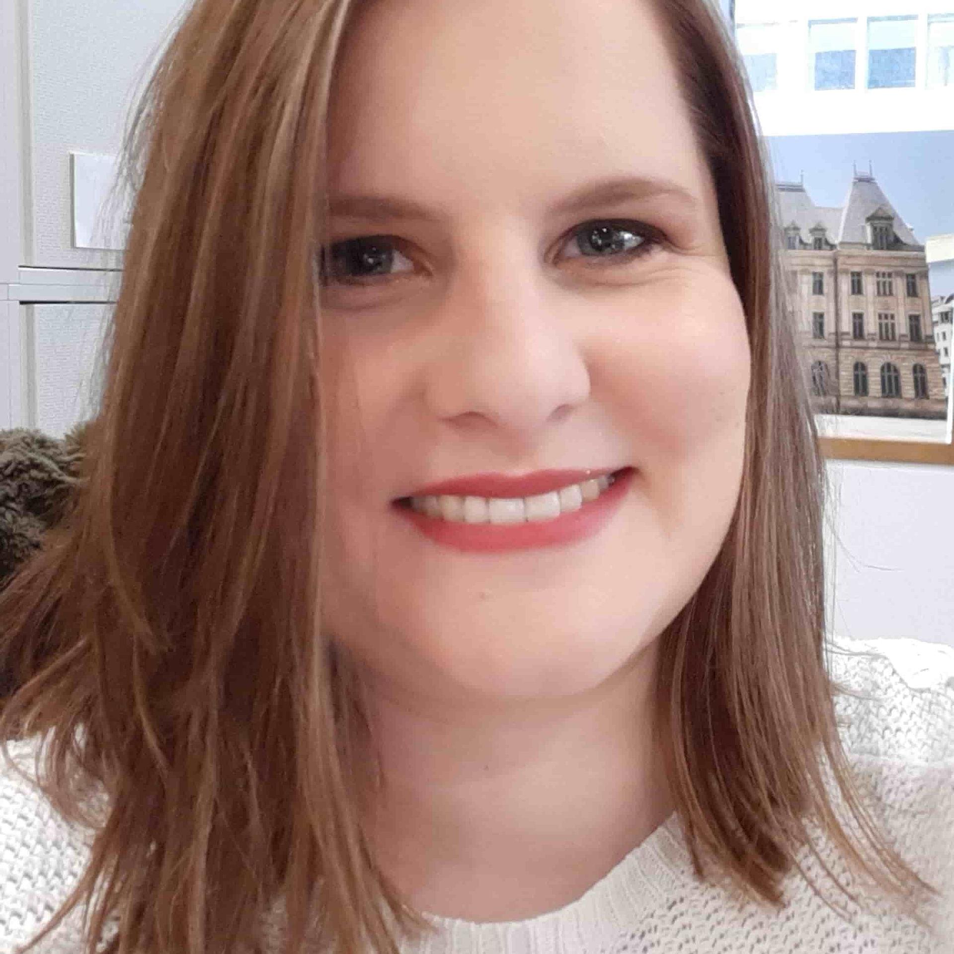 Caroline Blechschmidt Caroline Bleichschmidt sitzt lächelnd im Büro