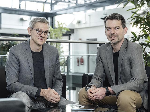 Zwei Männer sitzen nebeneinander in einem Foyer