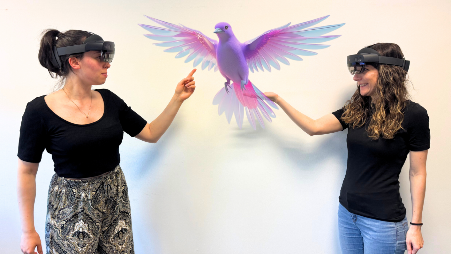 Zwei Frauen mit VR-Brille zeigen auf einen virtuellen Vogel in der Mitte des Bildes