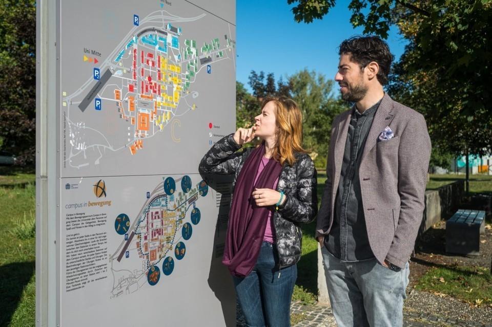 Eine Frau und ein Mann betrachten einen Campus-Plan