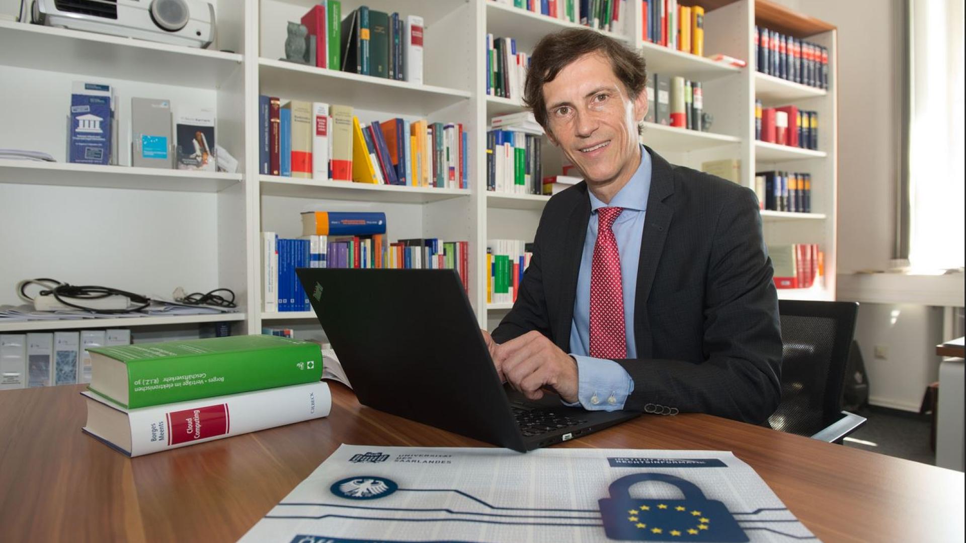 Mann mit Laptop vor einem Bücherregal