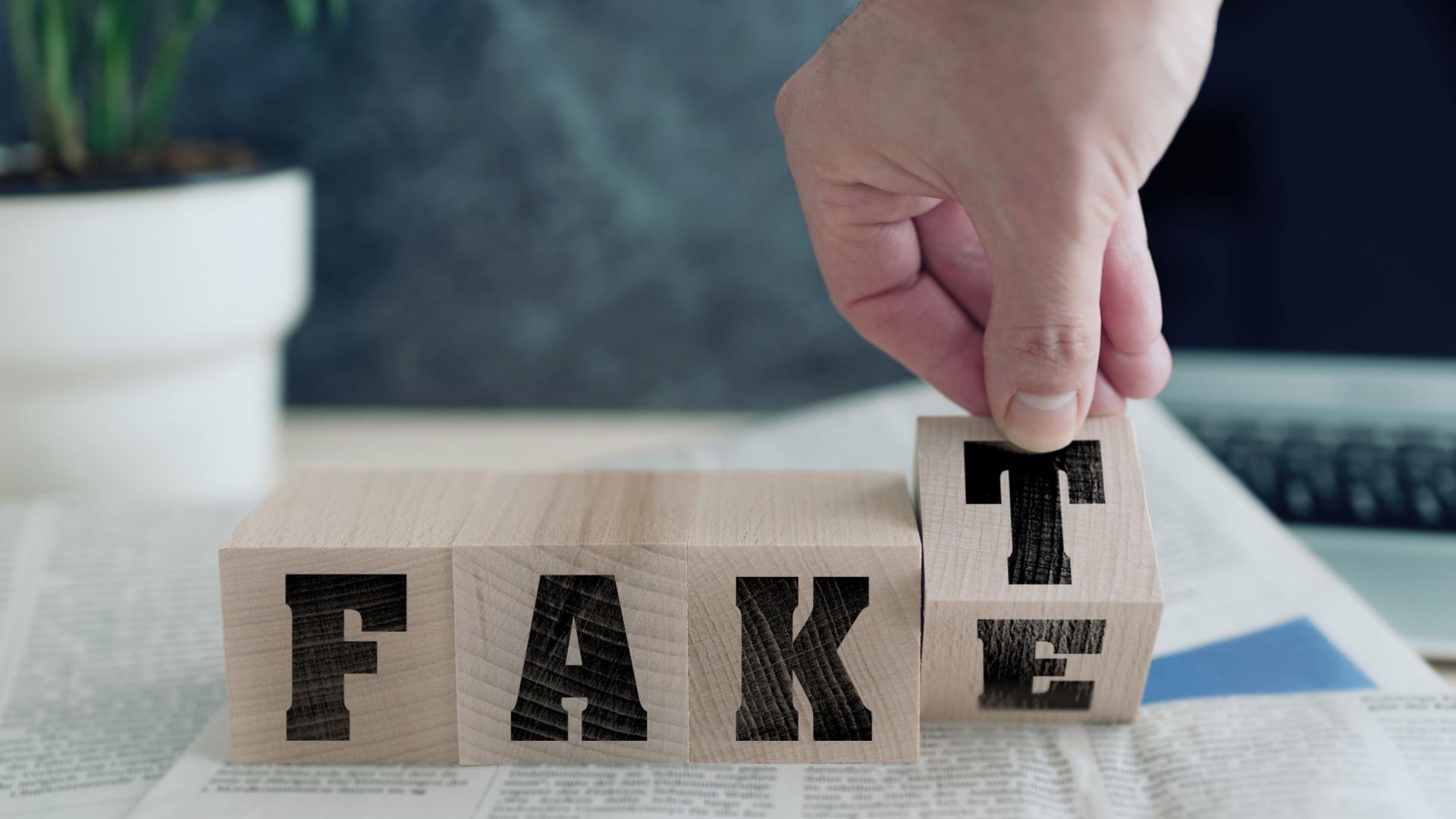 Ein Tisch mit Holzbuchstaben drauf, auf denen FAKE steht, der Buchstabe E ist halb gedreht und man erkennt den Buchstaben T, sodass man auch FAKT lesen kann