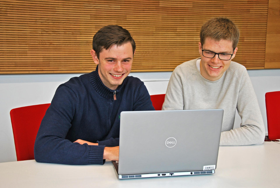 Simon Graf und Tim Kruse sitzen vor einem Laptop.