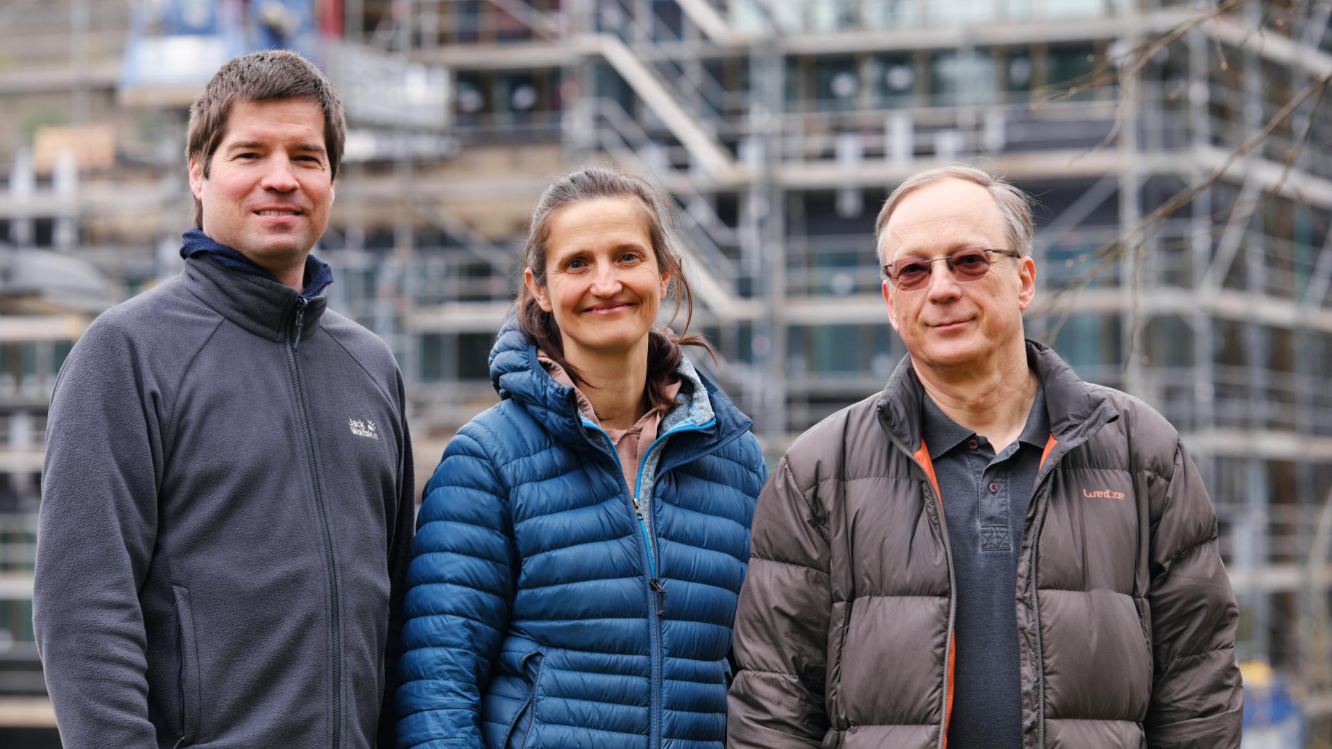 Drei zentrale Akteure der Saarbrücker Biophysik, Dr. Philipp Hövel, Prof. Franziska Lautenschläger und Prof. Albrecht Ott, im Frühjahr 2025 vor dem Rohbau des Zentrums für Biophysik