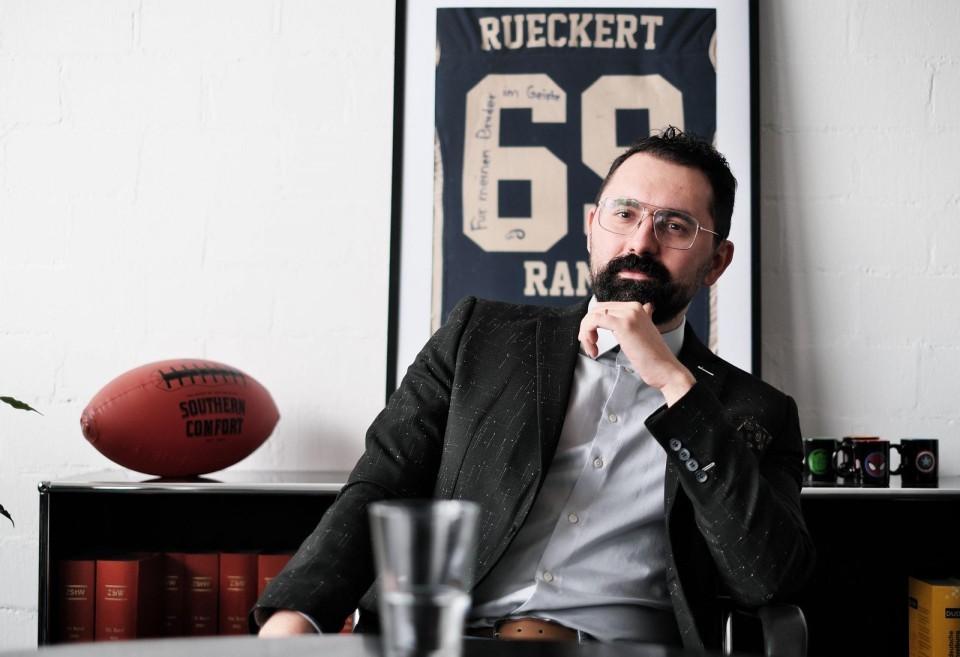 Mustafa Oğlakcıoğlu in seinem Büro. Im Hintergrund ein Football und das Trikot des Footballprofis Rückert