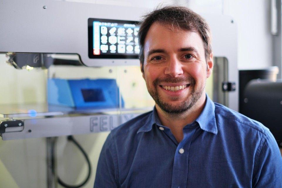 Juniorprofessor Benedikt Schnellbächer vor einem 3D-Drucker in seinem Labor