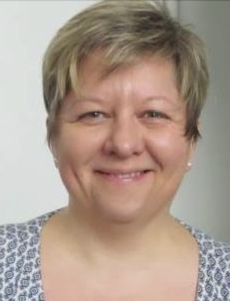 Lächelnde ältere Dame mit kurzen, blonden Haaren.