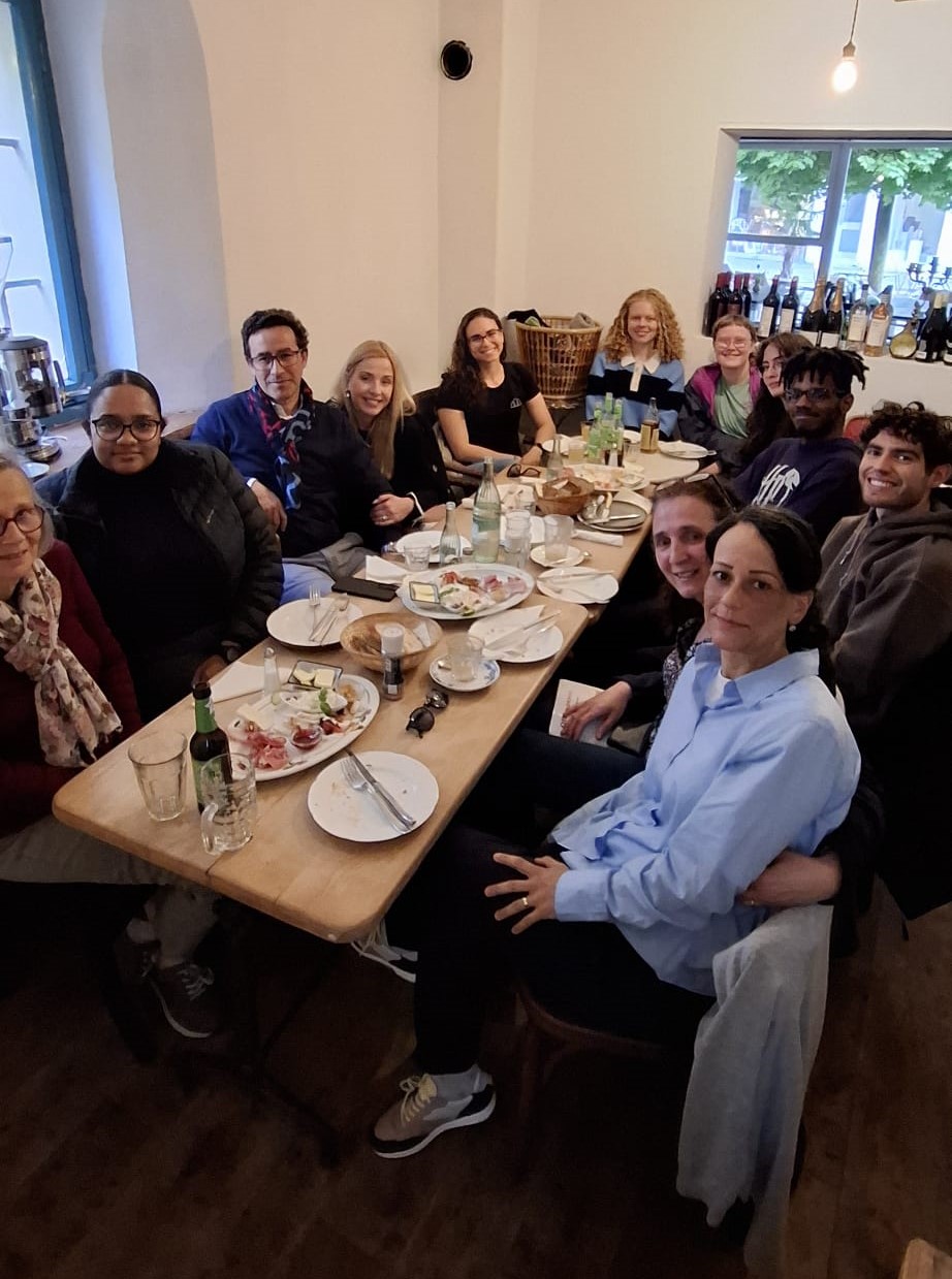 Studierende und Mitarbeitende der Universität des Saarlandes sitzen bei petiscos, portugiesischen Snacks, um einen langen Tisch herum und sprechen Portugiesisch.