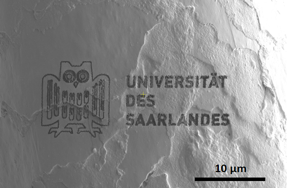 Das Logo der Universität des Saarlandes auf einer Fläche von 10 mal 10 µm ist mit Hlfe eines FIBs auf ein menschliches Haar aufgebracht.