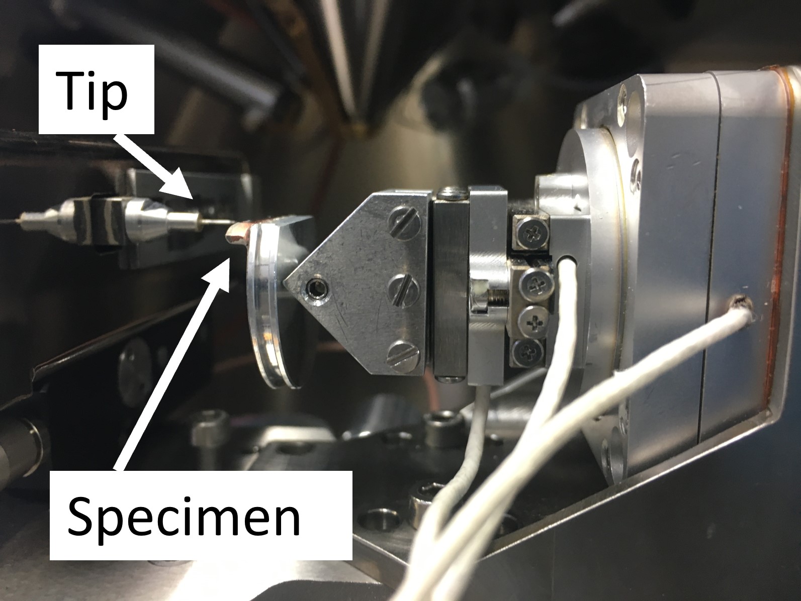 Gezeigt ist die dünne Spitze eines Nanoindenters, der horiztontal auf eine Probe ausgerichtet ist.