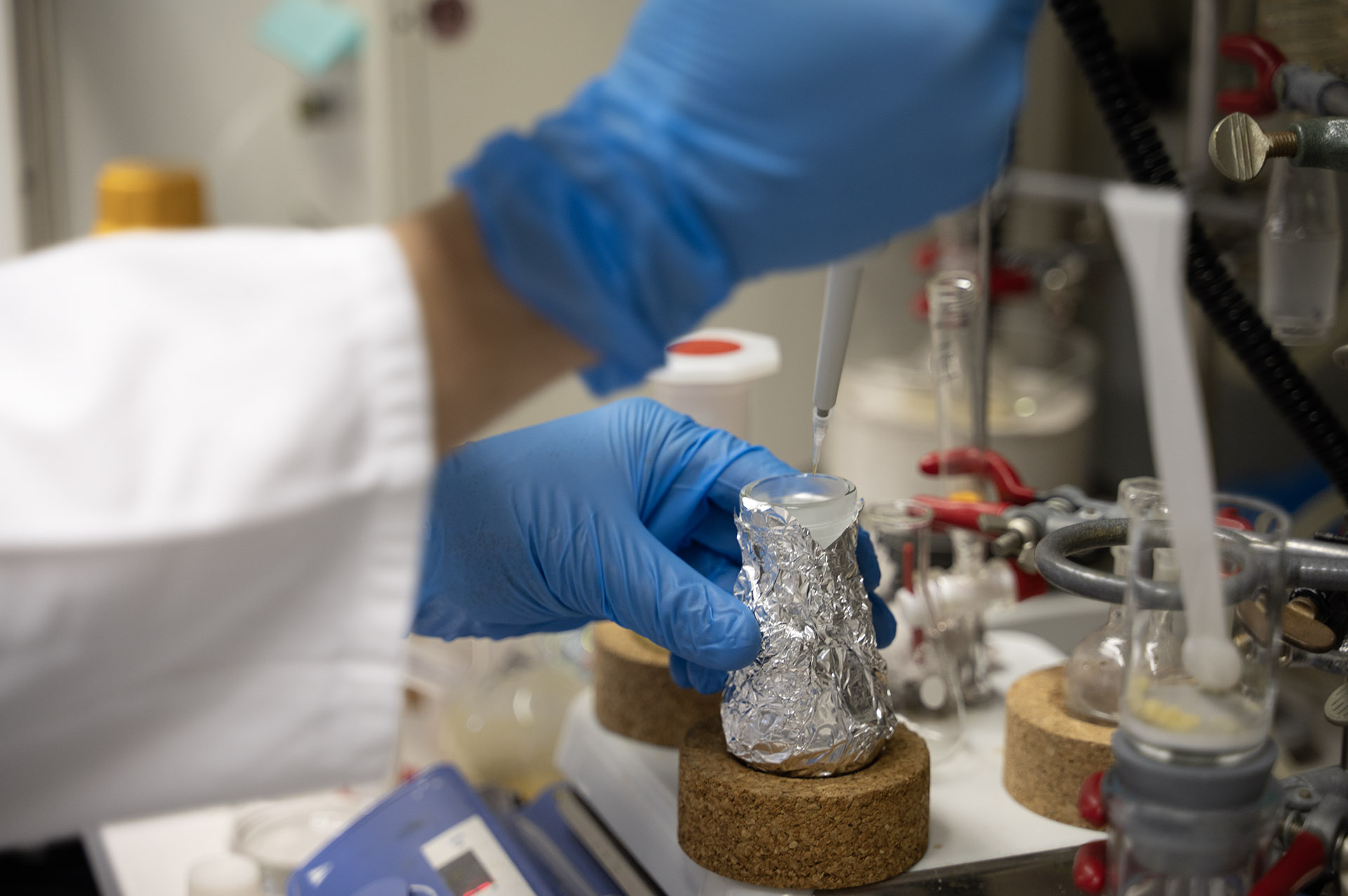 Nahaufnahme der Hände einer Laborfachkraft, die mit einer Pipette Flüssigkeiten aufnimmt.