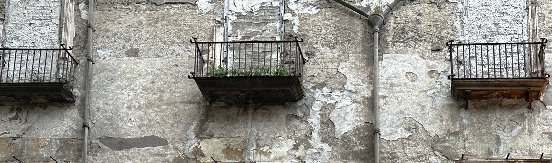 Fotografie dreier Balkone, bei welchen die Fenster zugemauert wurden. 