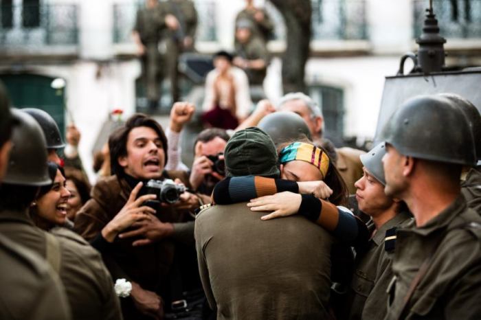 Frau und Mann (Militär) umarmen sich. Soldaten und Journalisten rundherum.
