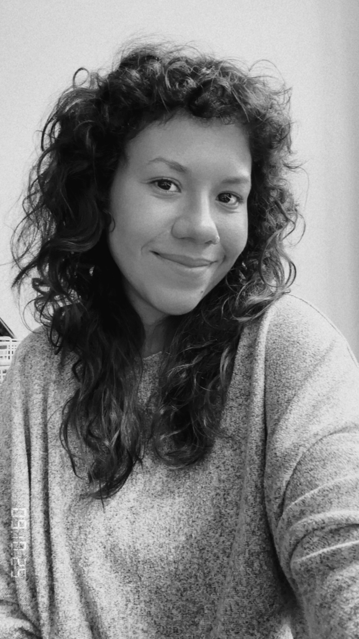 schwarz-weiß Foto von Person mit schulterlangen dunklen Locken und einer weißen Bluse