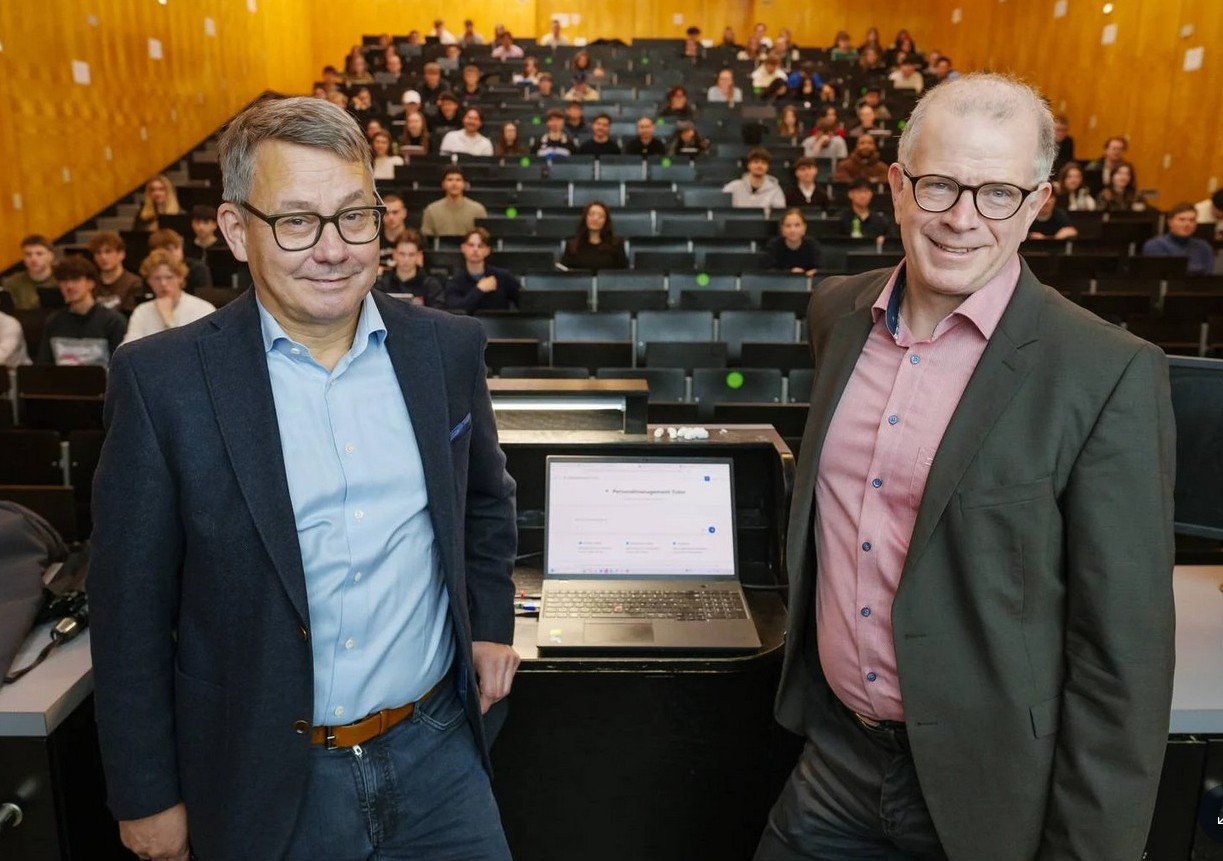 Das Foto zeigt Wirtschaftswissenschaftler Prof. Stefan Strohmeier und Prof. Christian Wagner (Physiker und Chief Digital Officer (CDO) der Uni) im Hörsaal mit Studierenden.